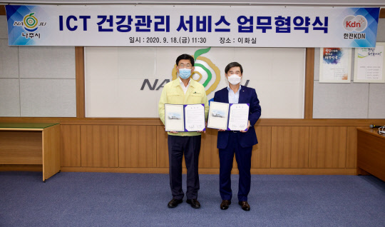 박성철 한전KDN 사장(오른쪽)과 강인규 나주시장이 지난 18일 정보통신기술(ICT) 기반의 건강관리 서비스 플랫폼 구축을 위한 업무협약을 체결한 뒤 협약서를 함께 들어보이고 있다. <한전KDN 제공>